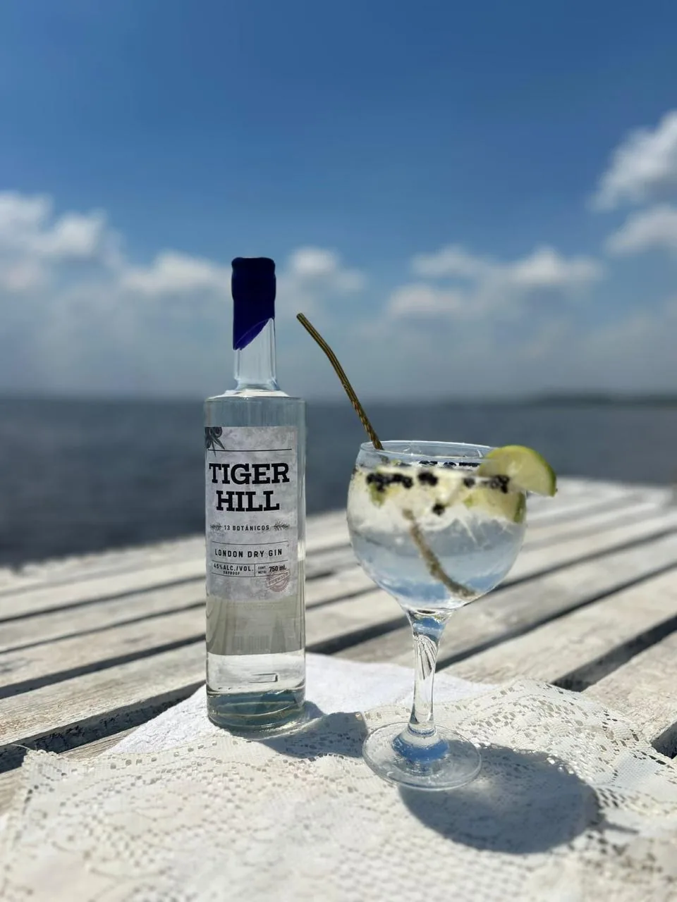 Botella de Tiger Hill y gin tonic sobre un muelle de madera